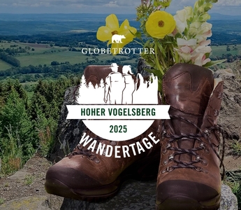 Wanderstiefel mit Blumen auf einem Felsen vor einer Landschaft mit Wald und Feldern, darüber das Logo und der Schriftzug "GLOBETROTTER HOHER VOGELSBERG 2025 WANDERTAGE"