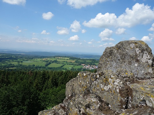 Panoramablick von einem Felsen über die grüne Landschaft mit Wolken am blauen Himmel.